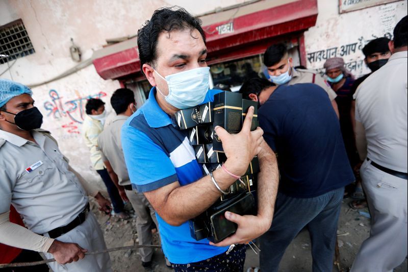 A man carries liquor after buying it at a wine store during an extended nationwide lockdown to slow down the spread of the coronavirus disease (COVID-19), in New Delhi, India, May 4, 2020. REUTERS/Adnan Abidi