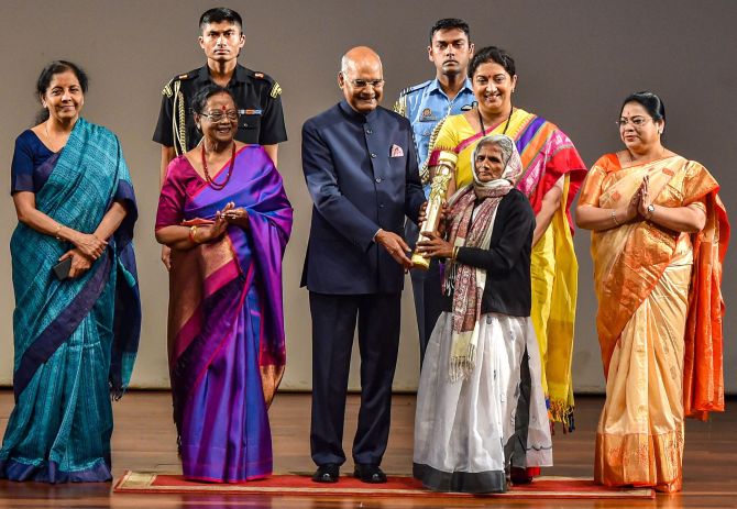 Kalavati Devi receives 'Nari Shakti Puraskar 2019' on International Women's Day from President Ram Nath Kovind as First Lady Savita Kovind, Union Ministers Smriti Irani and Nirmala Sitharaman look on, at Rashtrapati Bhavan Cultural Center in New Delhi, Sunday, March 8, 2020. Devi, a lady mason, has been a driving force towards reducing open defecation in the district of Kanpur. She is responsible for building more than 4000 toilets in villages. (PTI Photo/Manvender Vashist)