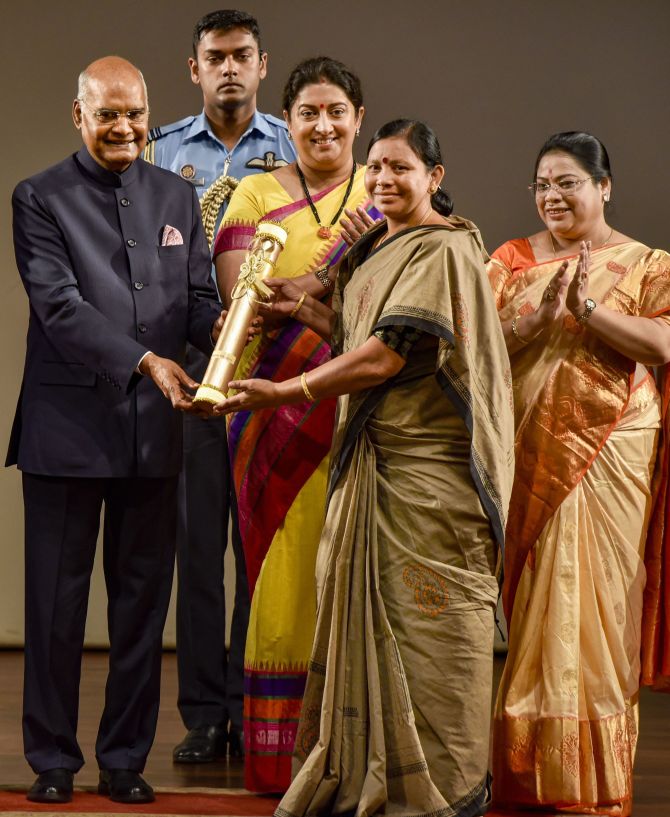 Padala Bhudevi receives 'Nari Shakti Puraskar 2019' on International Women's Day from President Ram Nath Kovind as Union Minister Smriti Irani looks on, at Rashtrapati Bhavan Cultural Center in New Delhi, Sunday, March 8, 2020. Bhudevi is a role model for women farmers and rural women entrepreneurs, working for development of tribal women, widows, Podu lands through a community based organisation. (PTI Photo/Manvender Vashist)