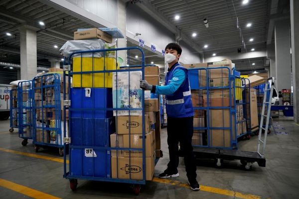 File picture of a delivery man for Coupang wearing a mask to prevent contracting the coronavirus, loading packages before leaving to deliver them in Incheon, South Korea on March 3, 2020. (REUTERS File Photo)