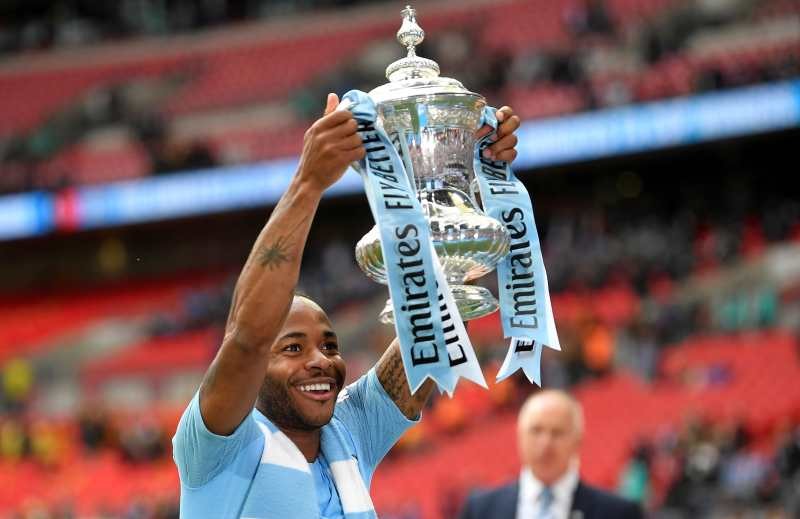 FILE PHOTO: Soccer Football - FA Cup Final - Manchester City v Watford - Wembley Stadium, London, Britain - May 18, 2019 Manchester City's Raheem Sterling celebrates winning the FA Cup final with the trophy REUTERS/Toby Melville/File Photo