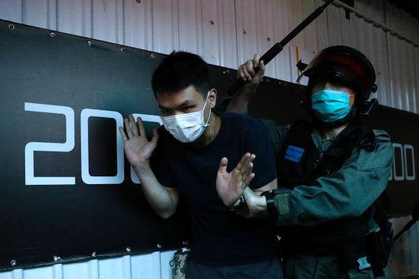 A detained anti-government protester is held by a riot police officer during a march against Beijing's plans to impose national security legislation in Hong Kong, China on May 24, 2020. (REUTERS Photo)