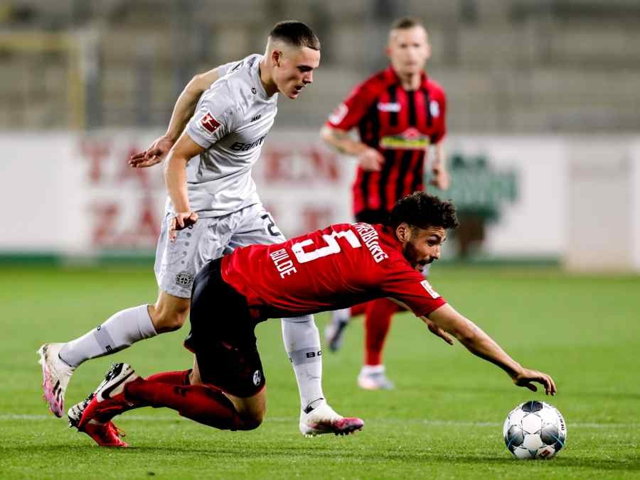 Freiburg's Manuel Gulde in action against Bayer Leverkusen's Florian Wirtz as play resumes behind closed doors following the outbreak of COVID-19. (Reuters Photo)