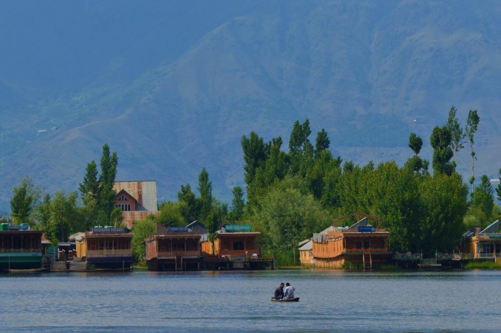 Kashmiri men row a boat at Dal Lake in front of empty house boats in Srinagar, Indian-administered Kashmir, June 1, 2020. Thomson Reuters Foundation/Athar Parvaiz