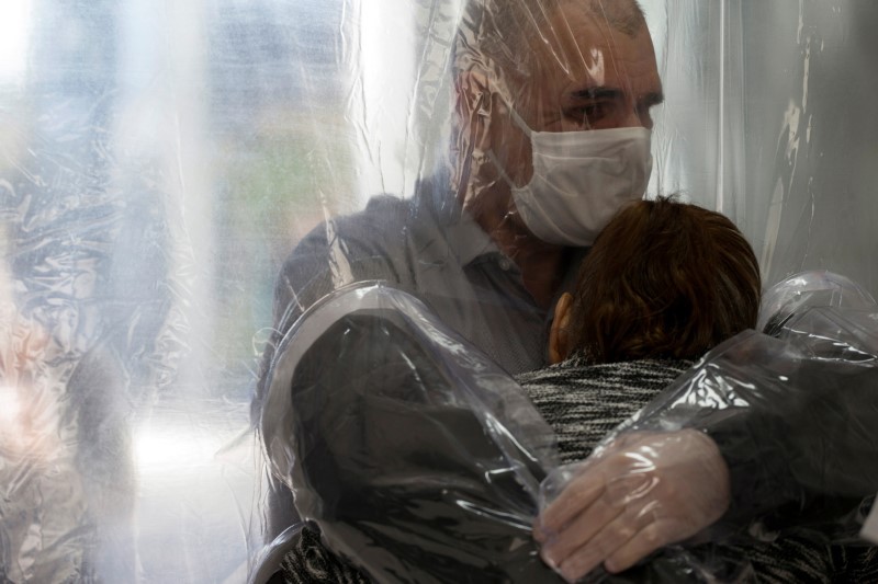 Ossimar Silva hugs his mother Carmelita Valverde, 85, through a plastic curtain at the 3i Bem-Estar - Residencial Senior nursing home, amid the coronavirus disease (COVID-19) outbreak, in Sao Paulo, Brazil May 30, 2020. Picture taken May 30, 2020.  (Reuters Photo)