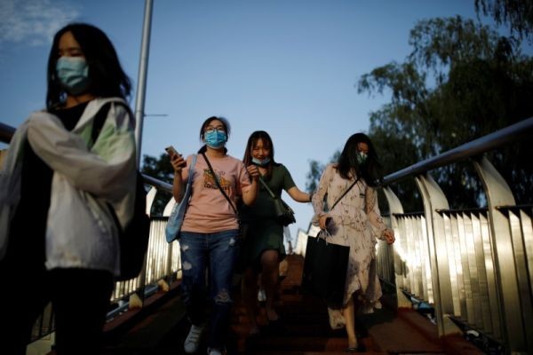 People wearing face masks following the coronavirus disease (COVID-19) outbreak walk on a footbridge in Beijing, China on June 4. (REUTERS Photo)