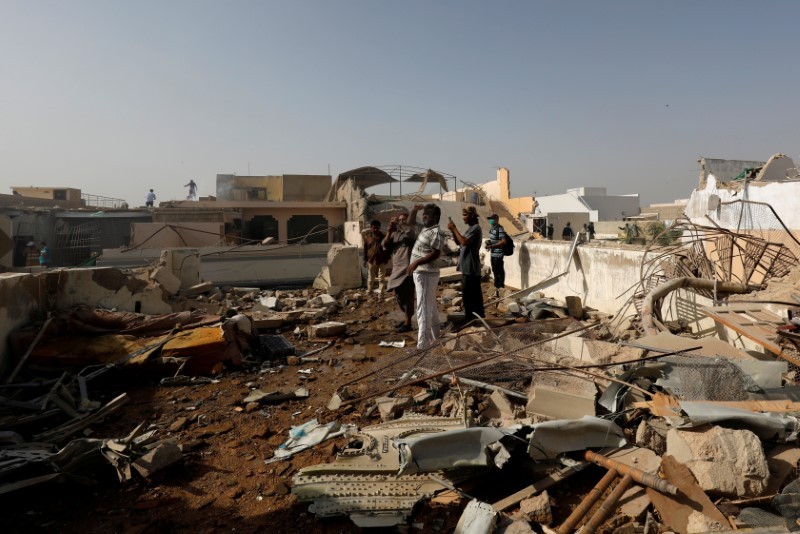 FILE PHOTO: People stand on a roof of a house amidst debris of a passenger plane, crashed in a residential area near an airport in Karachi, Pakistan May 22, 2020. REUTERS/Akhtar Soomro/File Photo