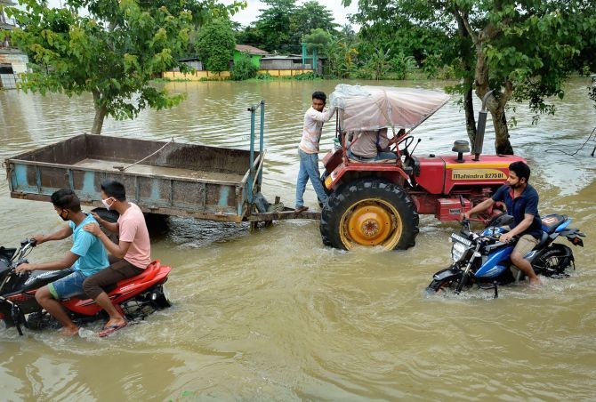  Commuters wade through a waterlogged street after rainfall, at Chamata in Nalbari district, Sunday, June 28, 2020. (PTI Photo)