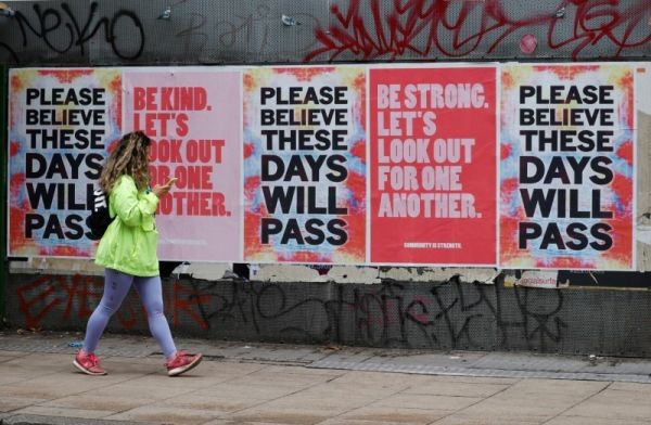 A woman walks by banners in Manchester, following the outbreak of the coronavirus disease (COVID-19), Manchester, Britain on June 3, 2020. (REUTERS Photo)