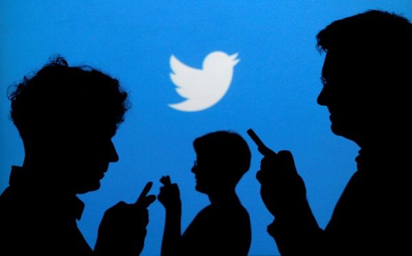 People holding mobile phones are silhouetted against a backdrop projected with the Twitter logo in this illustration picture taken in  Warsaw on September 27, 2013. (REUTERS File Photo)