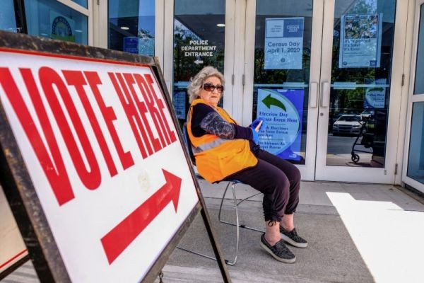 A poll deputy uses her cellphone as she wears gloves as a preventive measure against the outbreak of coronavirus disease (COVID-19) during the Democratic presidential primary election in Miami, Florida, US on March 17, 2020. (REUTERS File Photo)