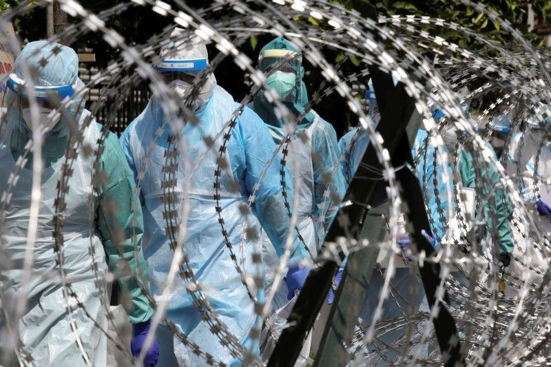 Medical workers wearing protective suits pass by barbed wire at the red zone under enhanced lockdown, amid the coronavirus disease (COVID-19) outbreak, in Petaling Jaya, Malaysia on May 11, 2020. (REUTERS File Photo)