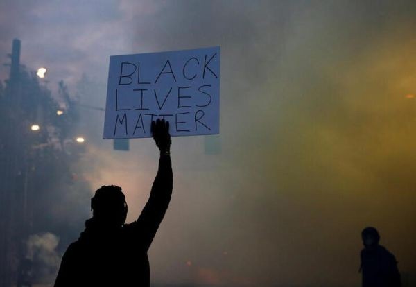 A person holds a "Black Lives Matter" sign as a heavy cloud of tear gas and smoke rises after being deployed by Seattle police as protesters rally against police brutality and the death in Minneapolis police custody of George Floyd, in Seattle, Washington, US on June 1, 2020.  (REUTERS Photo)