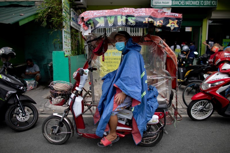 A rickshaw driver wearing makeshift protective suit and mask waits for passengers on his rickshaw lined with plastic as a makeshift protective measure against the coronavirus disease (COVID-19), in Manila, Philippines, May 28, 2020. REUTERS/Eloisa Lopez