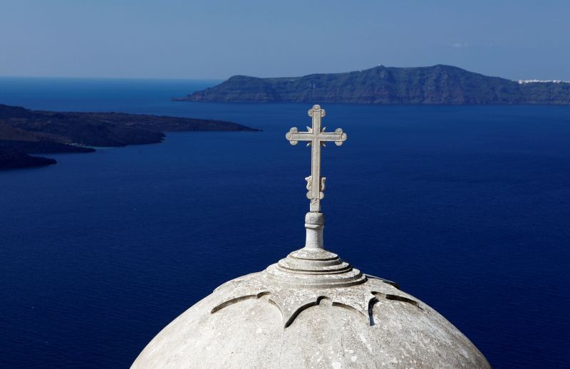 Volcanic islets are seen behind a Greek Orthodox church built on the edge of the caldera at the volcanic island of Santorini. (REUTERS File Photo)