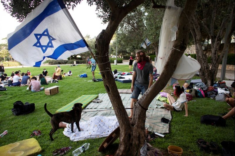 An Israeli flag flutters as people gather at a protest camp site, set up as part of on-going protests against Israeli Prime Minister Benjamin Netanyahu's alleged corruption and his government's handling of the coronavirus disease (COVID-19) crisis, at a park near Netanyahu's residence in Jerusalem on July 28, 2020. (REUTERS Photo)