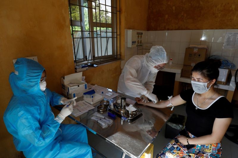 Medical specialists wearing protective suits collect blood sample from a woman who has returned after travelling to Da Nang, at a rapid testing center for coronavirus disease (COVID-19) outside Hanoi, Vietnam on July 30. (REUTERS Photo)