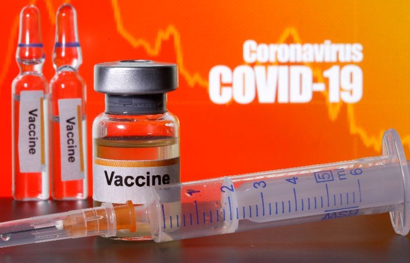 Small bottles labeled with "Vaccine" stickers stand near a medical syringe in front of displayed "Coronavirus COVID-19" words in this illustration taken April 10, 2020. REUTERS/Dado Ruvic/Illustration/File Photo