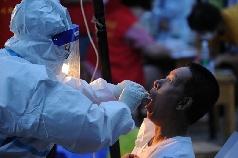 A worker in protective suit collects a swab from a man for nucleic acid testing at a makeshift testing site, following the coronavirus disease (COVID-19) outbreak in Dalian, Liaoning province, China on July 26, 2020. (REUTERS Photo)