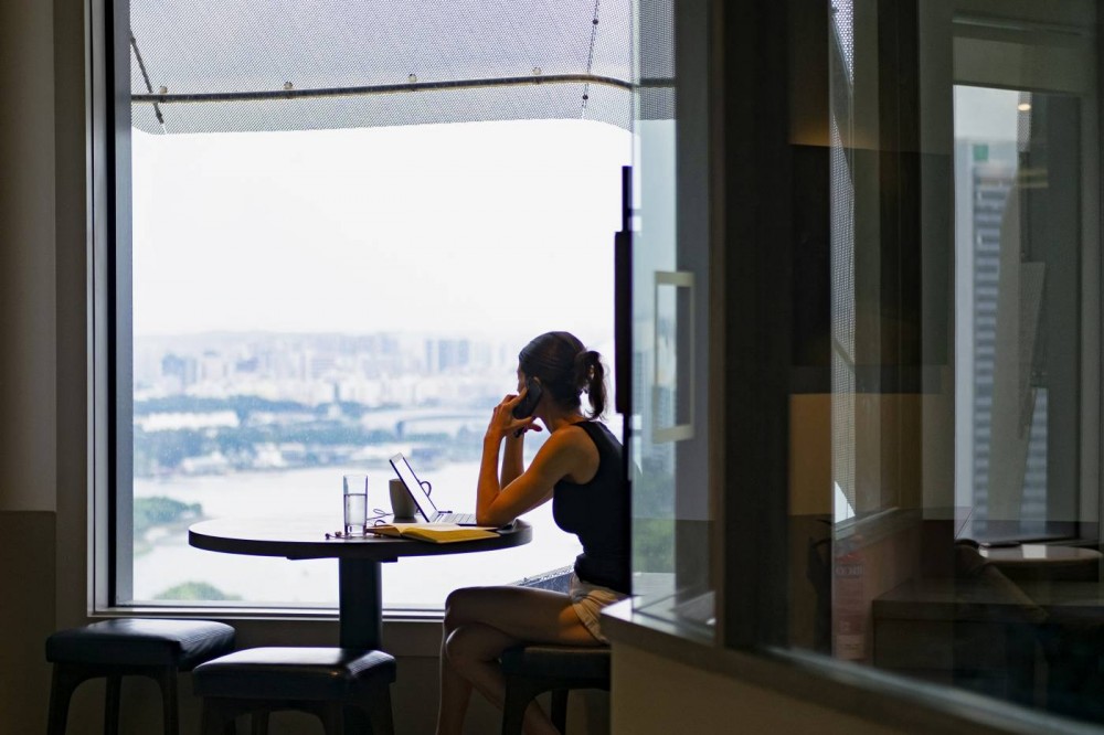 A woman answers a call while looking out the window in co-working space The Great Room's Centennial Tower location in Singapore, July 2, 2019. REUTERS/Loriene Perera