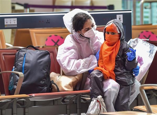 A passenger and her child wearing protective suits wait to board a plane at Kempegowda International airport, in Bengaluru,. PTI Photo