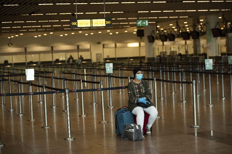 A passenger, wearing a face mask to protect against the spread of coronavirus, sits at the almost empty departures hall at the Zaventem international airport in Brussels. (Photo by Francisco Seco/AP Photo)