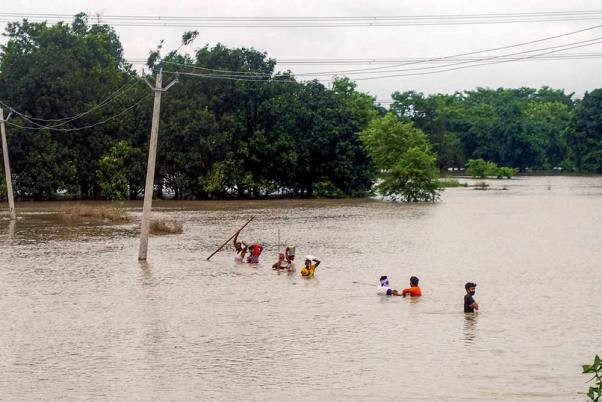 People wade through the floodwater as they move to a safer place, in Gopalganj district. PTI Photo