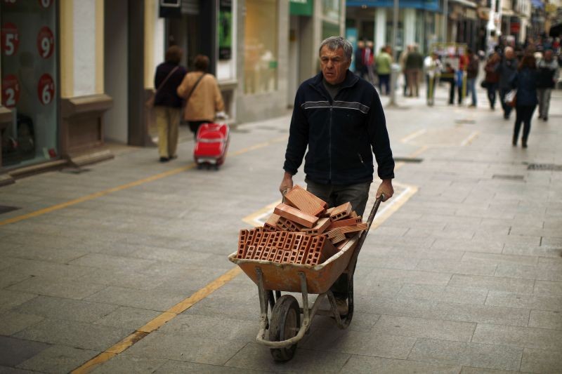 A construction worker pushes a wheelbarrow loaded with bricks in downtown Ronda, southern Spain on January 28, 2016.  (REUTERS File Photo)