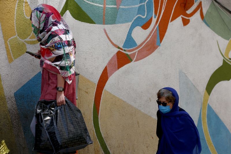 A woman wearing a protective face mask walks past a painted wall in a bazar following the outbreak of the coronavirus disease (COVID-19), north of Tehran, Iran on July 8, 2020. (REUTERS Photo)