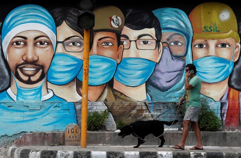 A man walks his dog past a graffiti on a road, amidst the spread of the coronavirus disease (COVID-19), in New Delhi on July 17, 2020. (REUTERS Photo)