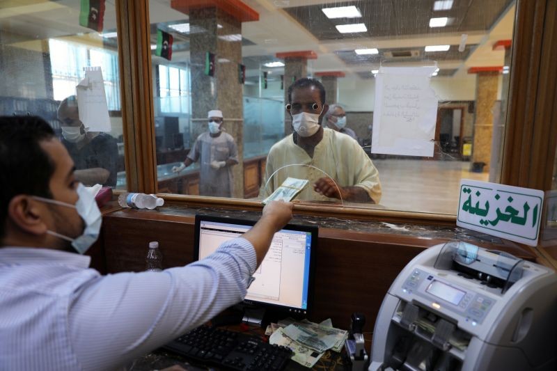 A Libyan man wearing a protective face mask receives money, following the outbreak of the coronavirus disease (COVID-19), at the North Africa Bank in Tripoli's Janzour city, Libya on June 10, 2020. (REUTERS File Photo)