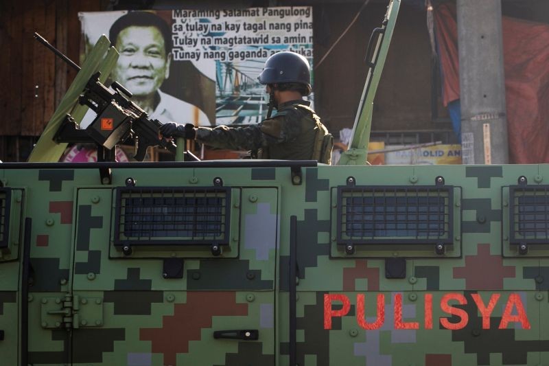 A police officer on board an armored vehicle drives past a poster of Philippines's President Rodrigo Duterte while patrolling a neighborhood to enforce the reimposed lockdown amid a spike in the coronavirus disease (COVID-19) cases, in Navotas, Metro Manila, Philippines on July 17, 2020. (REUTERS File Photo)