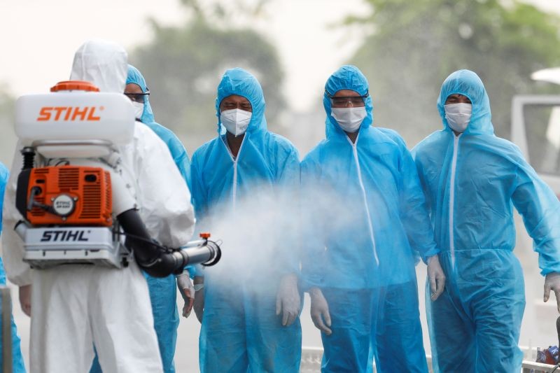 A health worker in a white protective suit sprays disinfectant at Vietnamese construction workers infected with the coronavirus disease (COVID-19), upon their arrival at the tropical diseases hospital after being repatriated from Equatorial Guinea via a specially-adapted Vietnam Airlines plane filled with medical equipment and negative pressure chambers, in Hanoi, Vietnam on July 29, 2020. (REUTERS Photo)