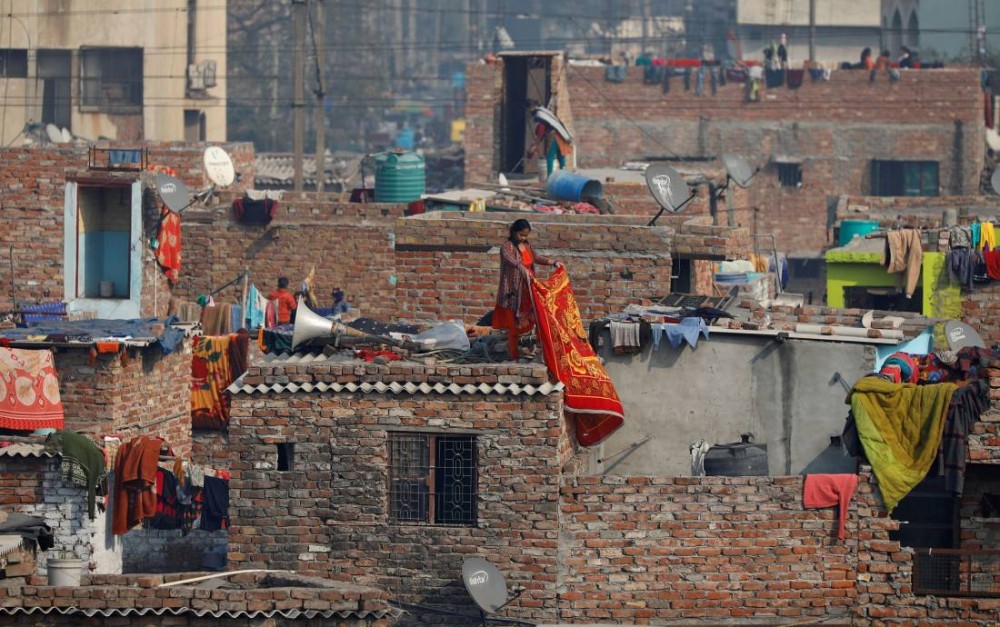 A woman hangs a blanket out to dry, at a slum in New Delhi, India January 2, 2020. REUTERS/Danish Siddiqui