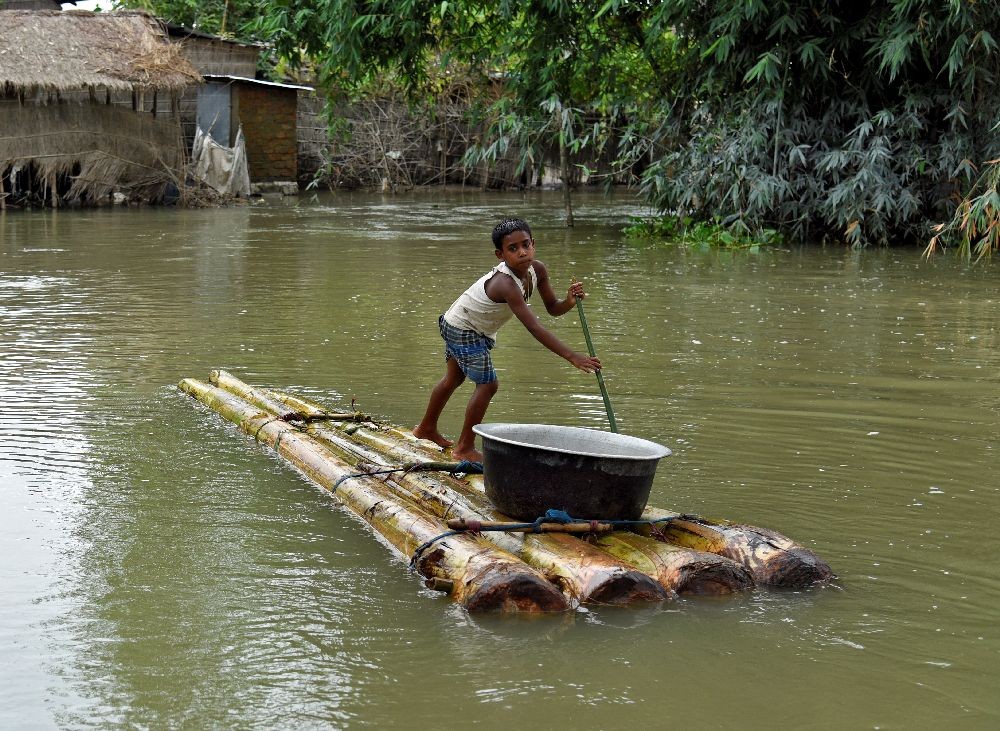 A boy transports a pot on a makeshift raft through a flooded area in Morigaon district, in the northeastern state of Assam, India, July 20, 2020. REUTERS/David Talukdar