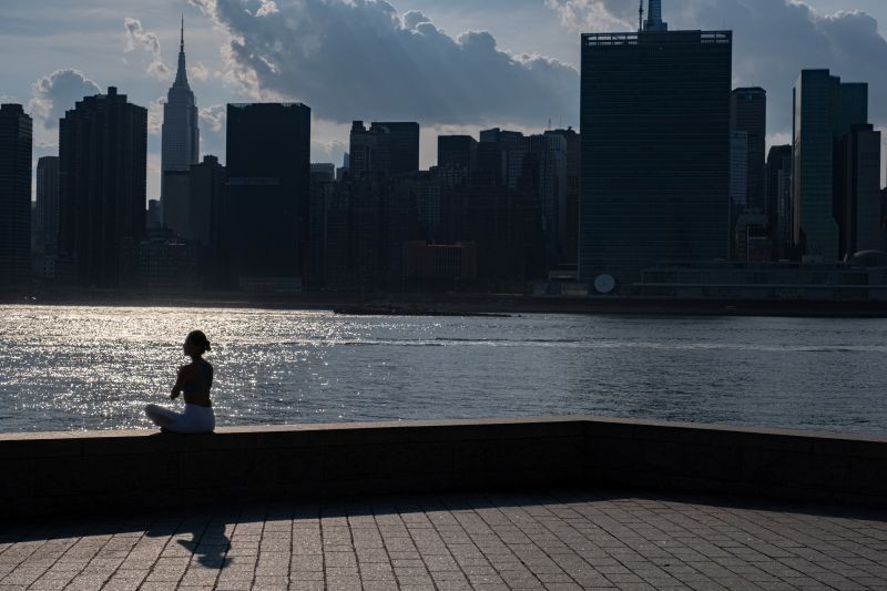 A woman meditates while enjoying a warm and humid day at Gantry Plaza State Park following the outbreak of the coronavirus disease (COVID-19), in Long Island City, New York, US on July 25, 2020. (REUTERS File Photo)