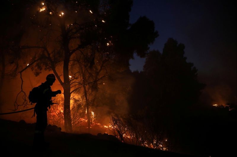 A firefighter sprays water to extinguish a wildfire burning near the village of Kechries, Greece on July 22, 2020. (REUTERS Photo)