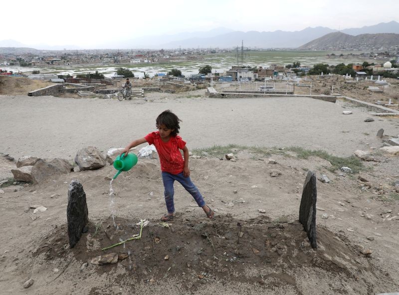 A girl spills water over the grave of twenty-four-year old Fatima Khalil, known as 'Natasha', who was killed in a bomb blast in Kabul, Afghanistan on June 30, 2020. (REUTERS File Photo)