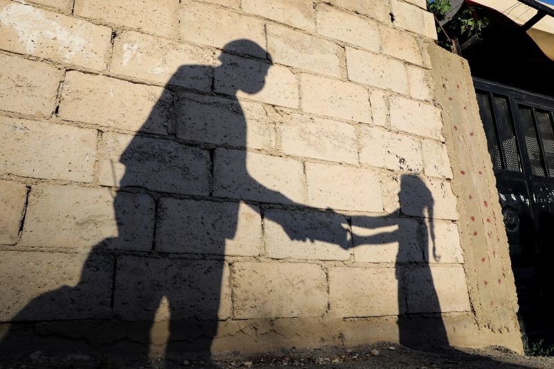 The shadow of a girl receiving a meal for iftar, or the evening meal, to break fast from a member of "Tkiyet Um Ali" humanitarian services center is cast on a wall in front of her family home in the city of Russeifa, during the holy fasting month of Ramadan, amid concerns over the spread of coronavirus disease (COVID-19), in Jordan on April 28, 2020. (REUTERS File Photo)