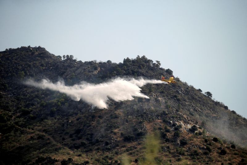 An airplane drops water as firefighters and Spanish Emergency Military Unit (UME) battle a wildfire in Robledo de Chavela, near Madrid, Spain on August 3. (REUTERS Photo)