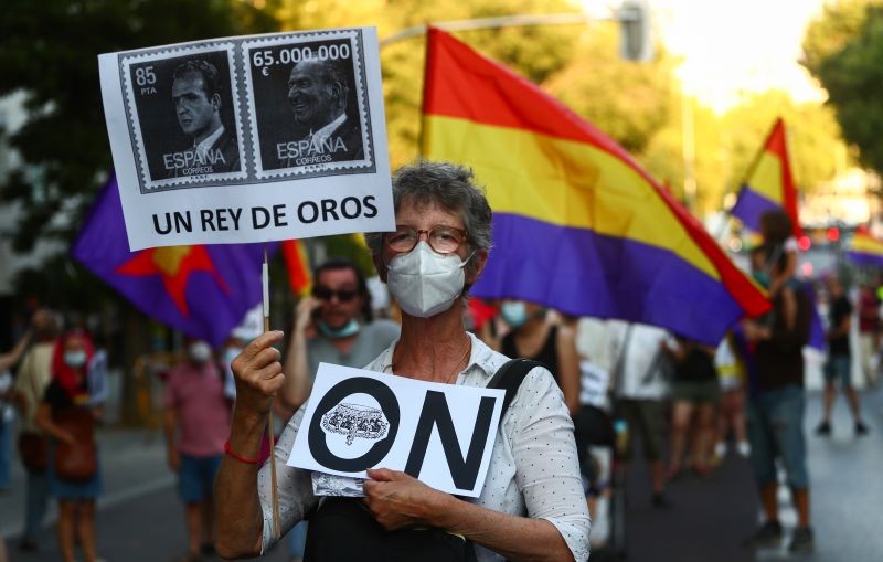 A protester wearing a protective face mask holds a banner reading "a king of gold" during a demonstration against Spanish monarchy amid allegations of corruption against former Spain's King Juan Carlos, in Madrid, Spain on July 25, 2020. (REUTERS File Photo)