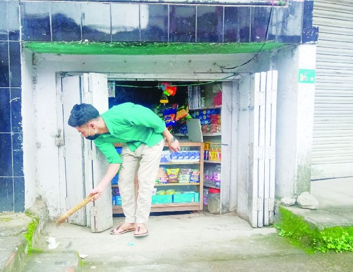 A salesman sweeps outside his shop to resume activities after the two week long total lockdown was lifted in Kohima on Saturday. (Morung Photo)