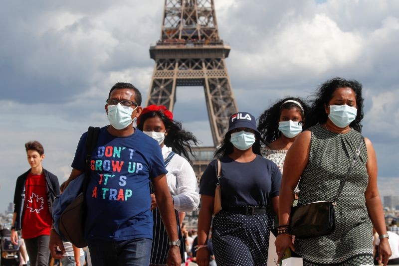 People wearing protective face masks walk at the Trocadero square near the Eiffel Tower in Paris as France reinforces mask-wearing as part of efforts to curb a resurgence of the coronavirus disease (COVID-19) across the country on August 3, 2020. (REUTERS Photo)