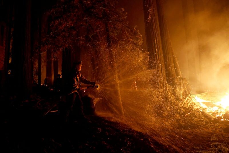 Cal Fire firefighter Anthony Quiroz douses water on a flame as he defends a home during the CZU Lightning Complex Fire in Boulder Creek, California, US on August 21, 2020. (REUTERS Photo)