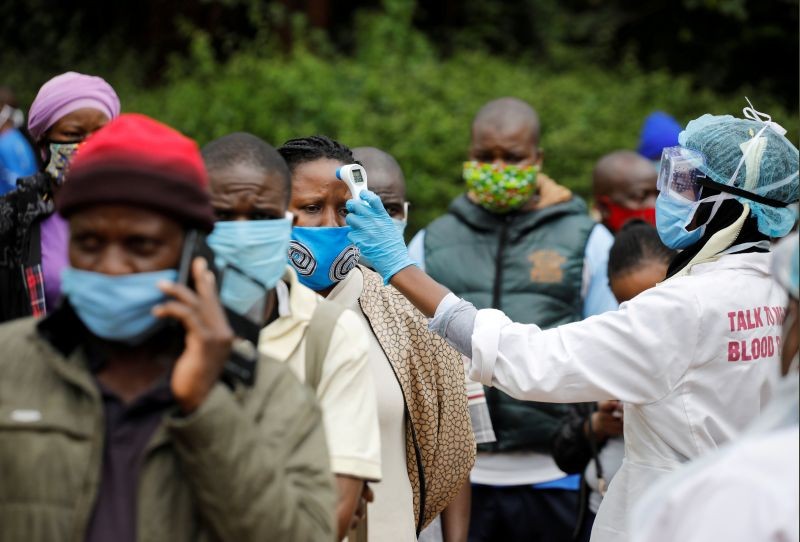 A health worker takes the temperature of a person standing in line for mass testing in an effort to stop the spread of the coronavirus disease (COVID-19) in the Kibera slum of Nairobi, Kenya on May 26, 2020. (REUTERS File Photo)
