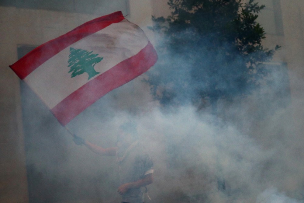 A demonstrator waves a Lebanese flag during anti-government protests that have been ignited by a massive explosion in Beirut on August 10, 2020. (REUTERS/Hannah McKay)