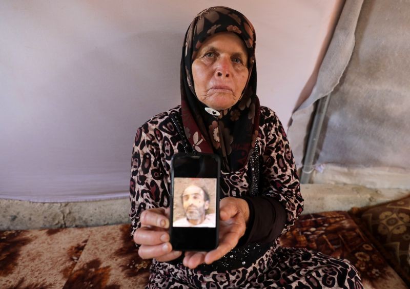 Fouziya al-Ghajar, 75, displays a picture of her deceased brother on a mobile phone, that she says was identified among thousands of images, smuggled out of Syria by a former Syrian military photographer code-named Caesar, that show bodies of dead detainees in Syrian government detention facilities, at an internally displaced persons camp tent in the opposition-held Idlib, Syria, July 11, 2020.  (REUTERS Photo)