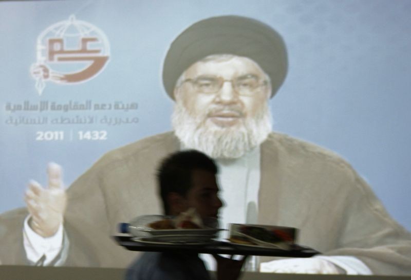 Lebanon's Hezbollah leader Sayyed Hassan Nasrallah speaks on television, as a waiter serves food at a restaurant in the port-city of Sidon, southern Lebanon August 17, 2011. Nasrallah said an indictment accusing four members of the militant Shi'ite group of taking part in killing statesman Rafik al-Hariri contained "no direct evidence" against them. Nasrallah delivered the speech during an Iftar, the evening meal with which Muslims break their fast during the Islamic month of Ramadan, held by the women of the Islamic Resistance Support Association in Lebanon. (REUTERS File Photo)