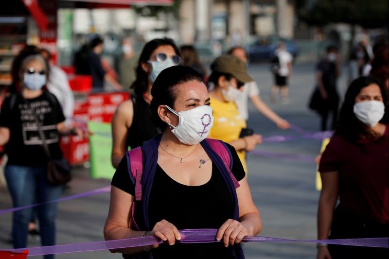 Women wearing protective face masks keep social distance by holding onto purple ribbons as they protest for women rights and against child abuse, amid the spread of the coronavirus disease (COVID-19), in Istanbul, Turkey on May 20, 2020. (REUTERS File Photo)