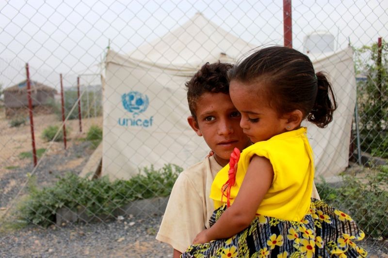 A boy carries his sister as he stands in front of the fence of a closed clinic at a camp for internally displaced people near Abs of Hajjah province, Yemen on August 19, 2020. (REUTERS File Photo)